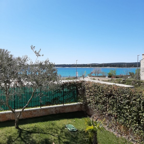 Vue depuis le jardin, par-dessus la rue, sur la baie turquoise