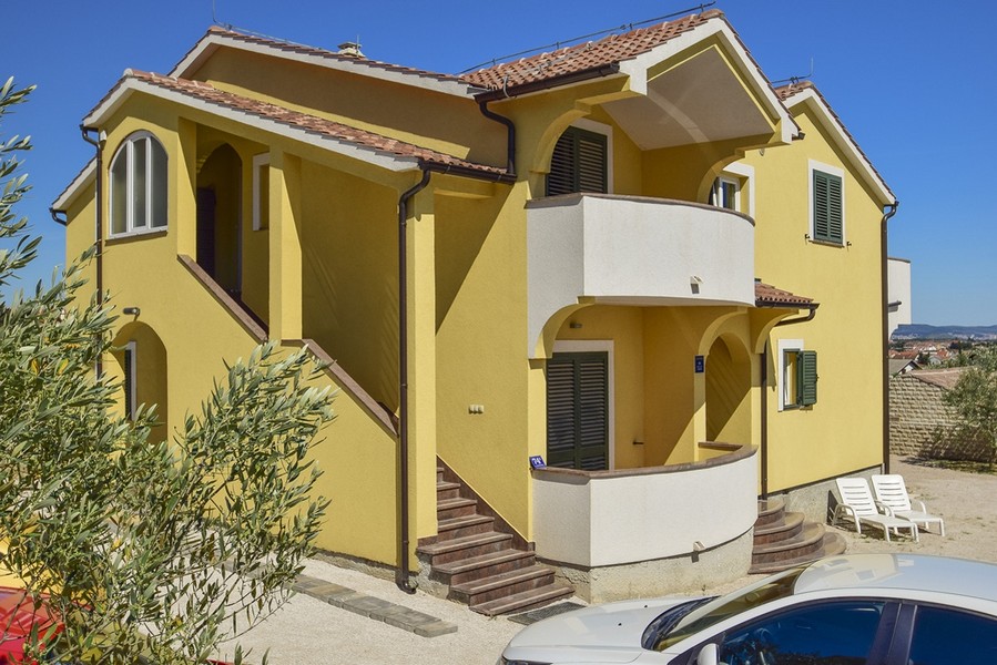Maison jaune avec balcon rond et escalier extérieur