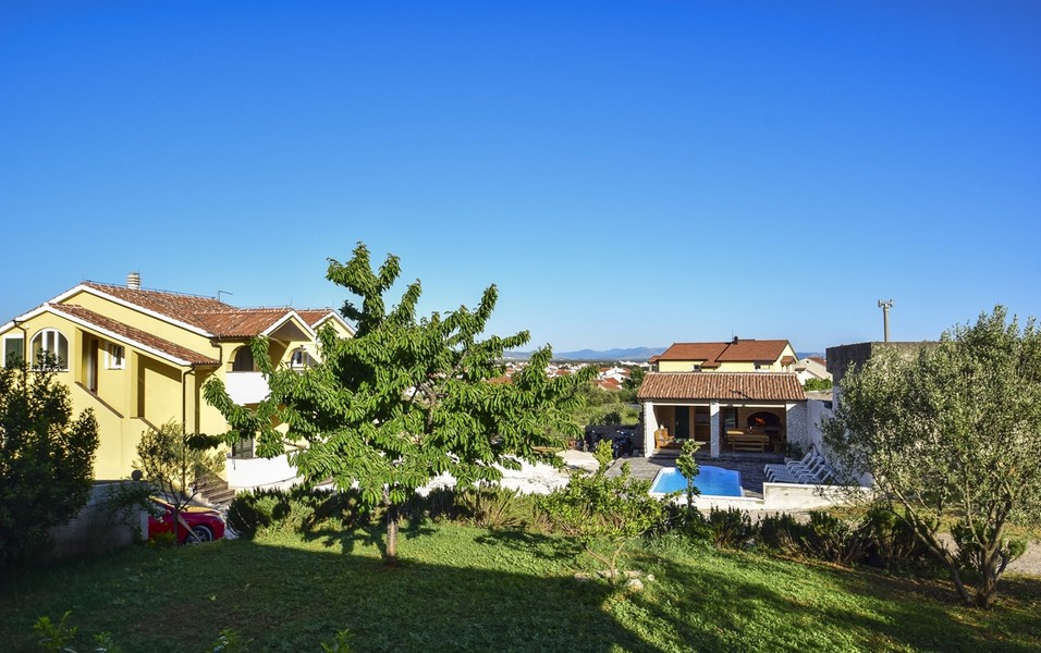 Jardin avec arbre fruitier et vue sur la piscine et la dépendance