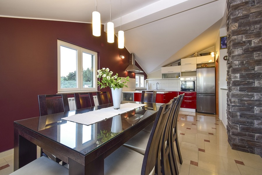 Table à manger devant le mur rouge avec cuisine derrière
