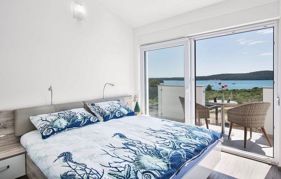 Chambre avec porte-fenêtre ouverte sur la baie