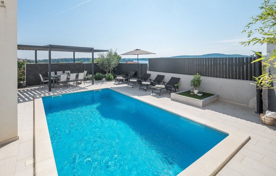 Piscine avec transats et pergola derrière le mur sombre
