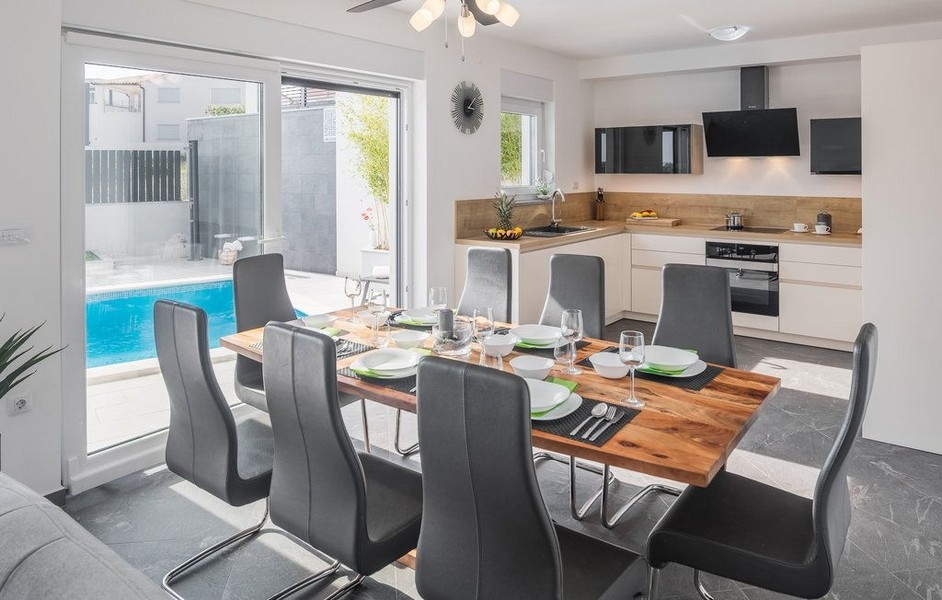 Table à manger dressée à côté de la cuisine avec vue sur la piscine