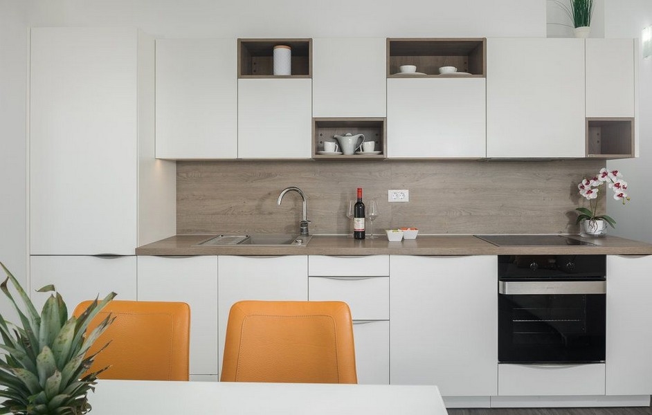 Cuisine linéaire blanche avec fond en bois et chaises orange