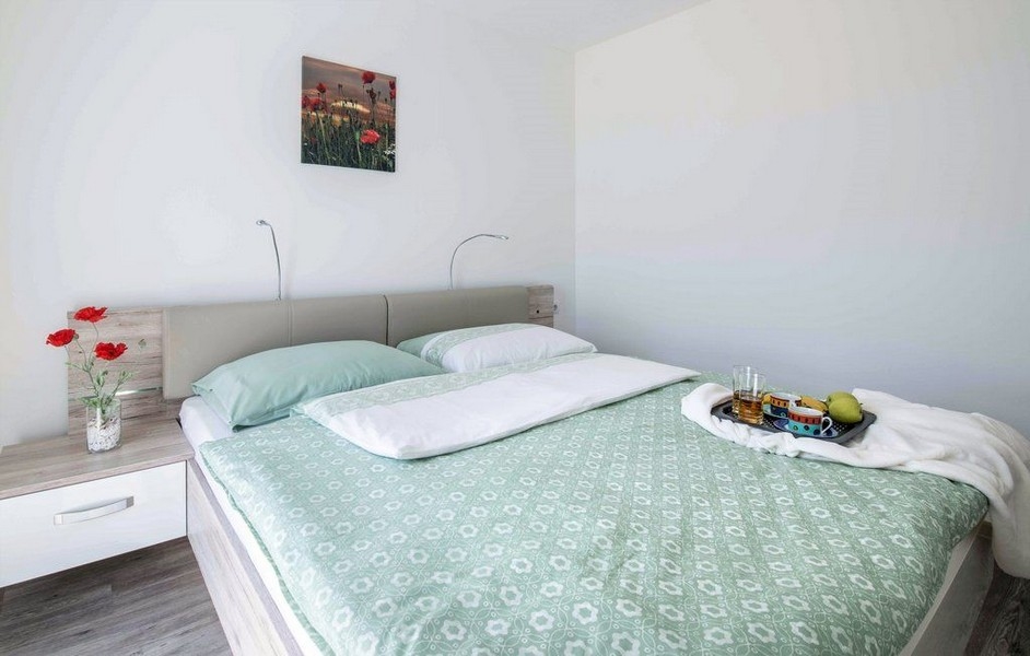 Chambre avec linge de lit vert et tableau de coquelicots