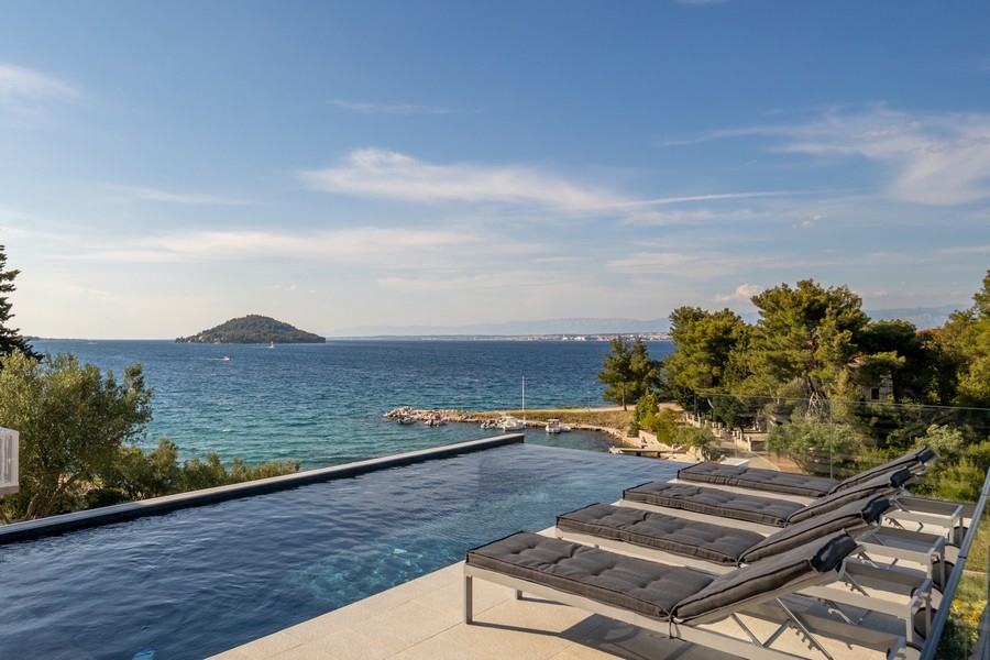 Piscine à débordement avec transats et vue sur le petit îlot