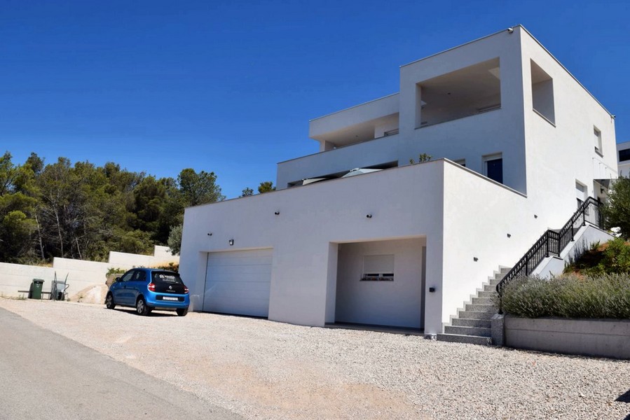 Villa blanche avec garages et escalier extérieur à flanc de colline