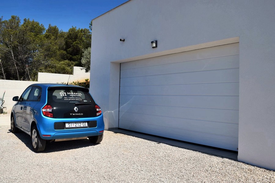 Porte de garage à côté de l'allée gravillonnée