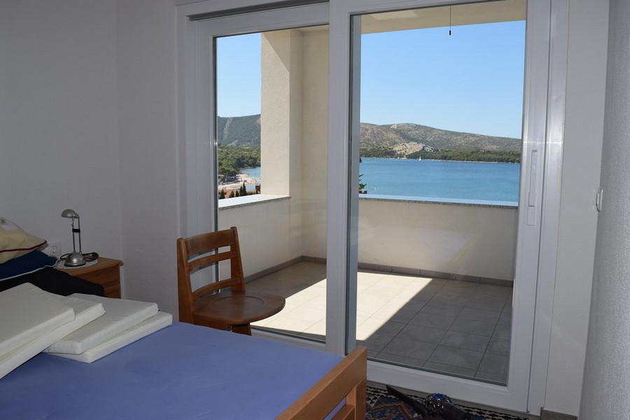 Chambre avec porte ouverte sur le balcon au-dessus de la baie