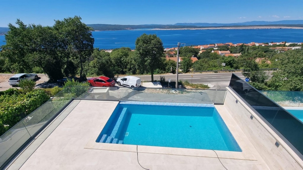 Piscine avec garde-corps en verre et vue par-dessus la route sur la baie