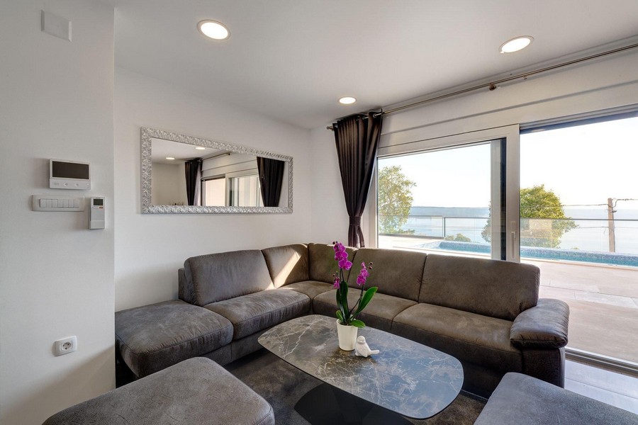 Séjour avec canapé d'angle gris et miroir au mur