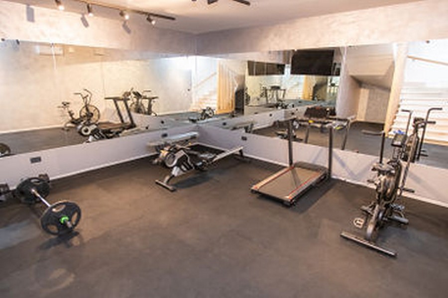 Salle de sport avec tapis de course, haltères et mur de miroirs