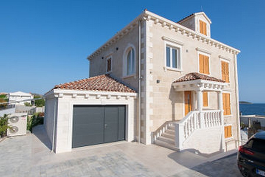 Villa en pierre avec escalier extérieur et garage dans la cour d'entrée