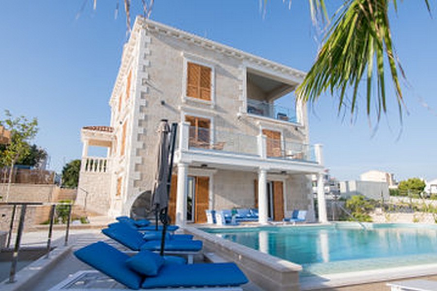Villa en pierre naturelle claire avec piscine et bains de soleil bleus