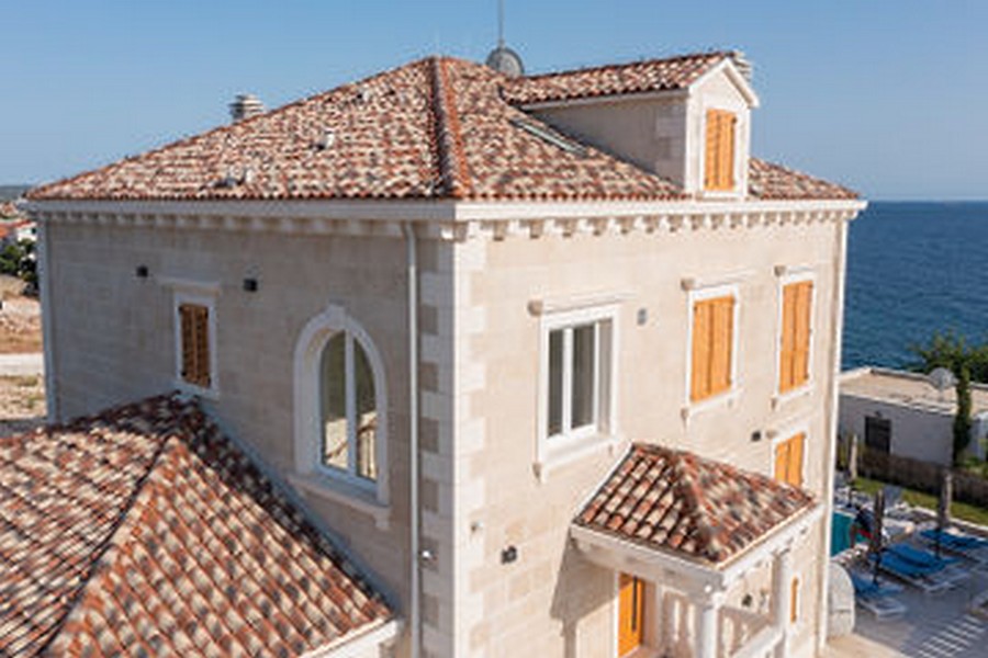 Villa en pierre avec toit en tuiles et volets en bois au bord de la mer
