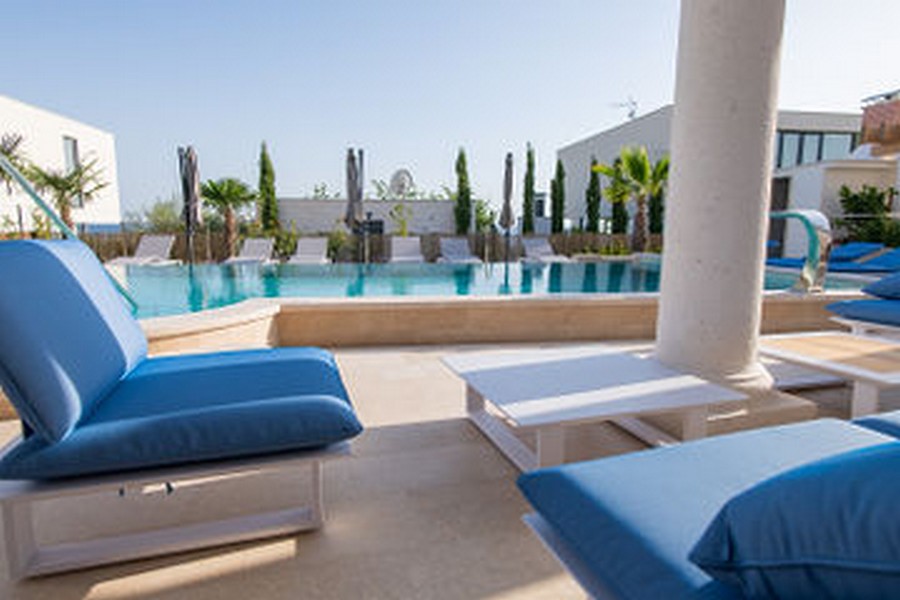 Mobilier lounge bleu au bord de la piscine avec cyprès derrière
