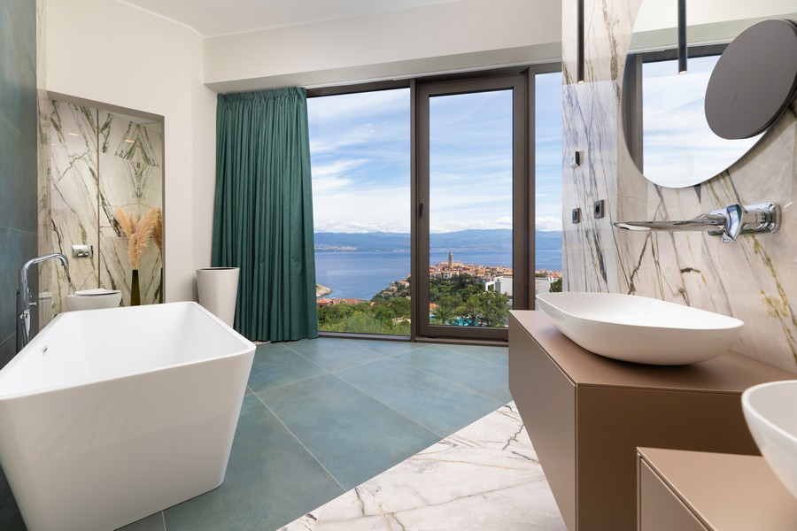 Salle de bains avec baignoire îlot et fenêtre donnant sur la côte