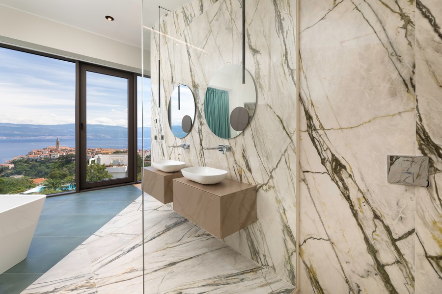 Double vasque devant le mur en marbre avec miroirs ronds