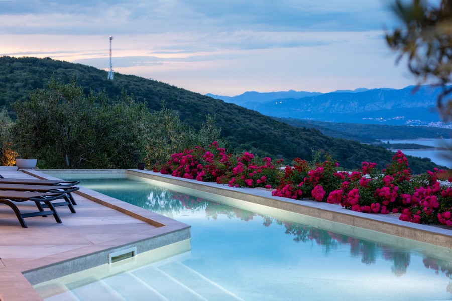 Piscine avec transats et roses rouges au-dessus de la vallée