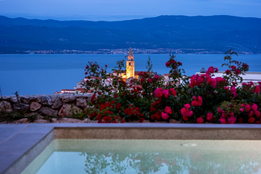 Vue par-dessus des roses sur le clocher éclairé le soir