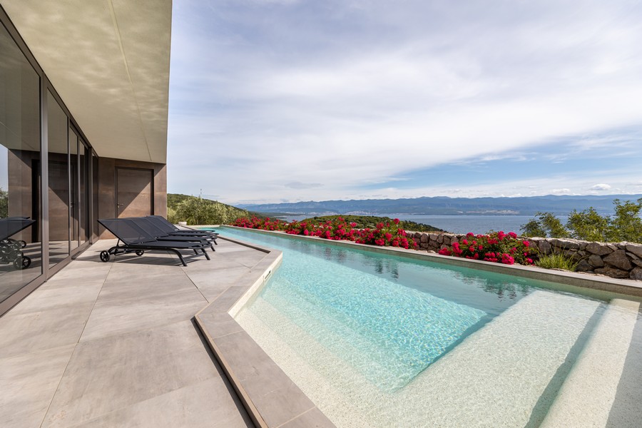 Piscine à débordement avec massif de fleurs et vaste vue sur la mer
