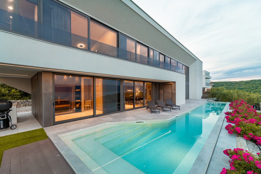 Piscine le long de la façade vitrée avec lauriers-roses au bord