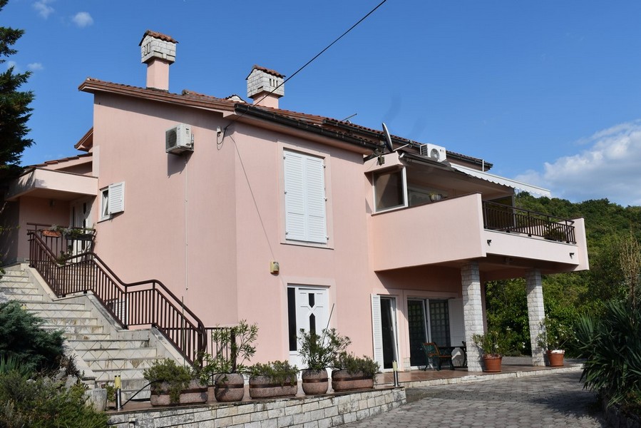 Maison rose avec escalier extérieur et balcon sur colonnes