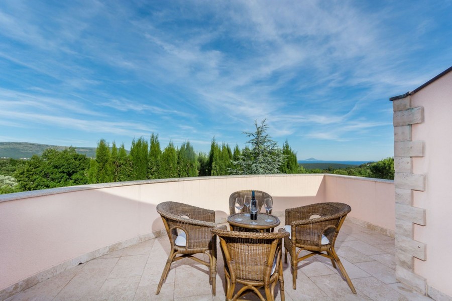 Balcon arrondi avec mobilier en rotin et du vin sur la table
