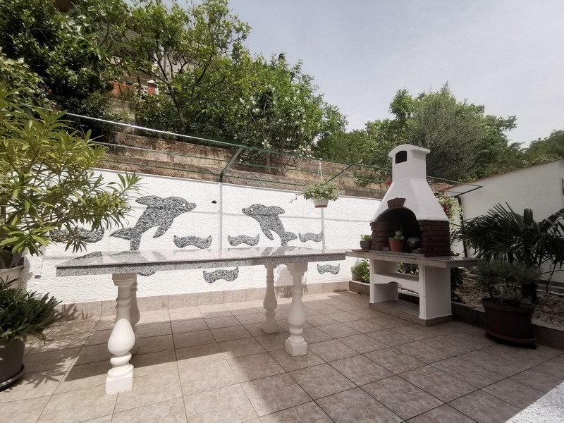 Terrasse avec barbecue maçonné et mosaïque de dauphins au mur