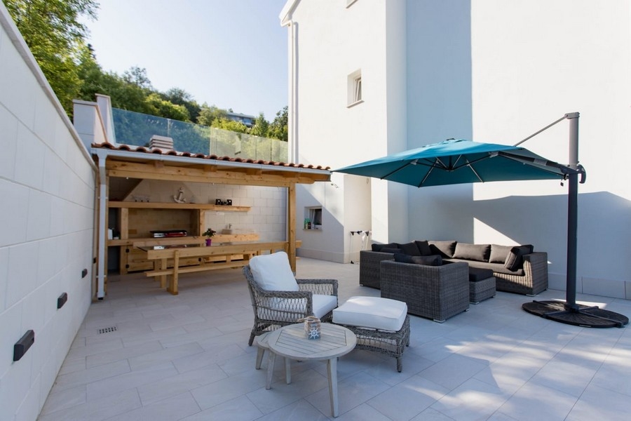Terrasse couverte avec coin lounge et parasol