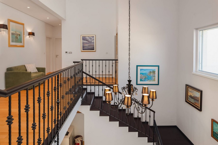 Escalier avec rambarde en fer forgé et grand lustre