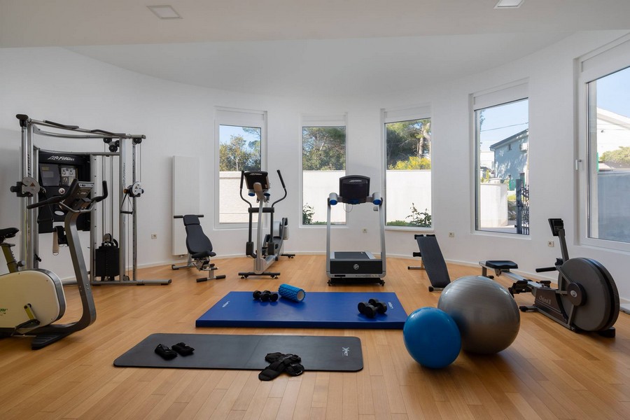 Salle de sport avec station de musculation, tapis de course et ballons de gymnastique