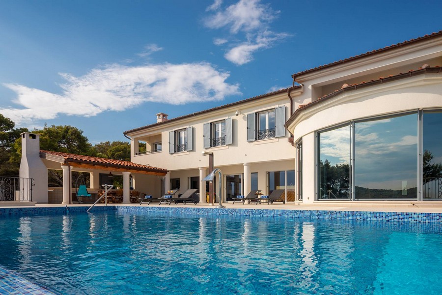 Villa avec fenêtre ronde et longue piscine sous un ciel bleu