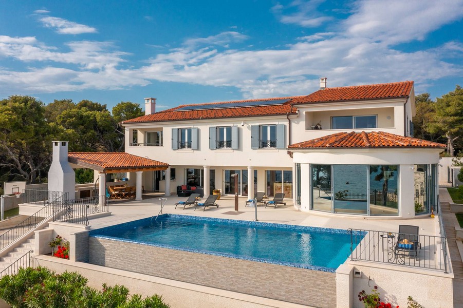 Villa avec toit en tuiles et piscine au-dessus du rivage