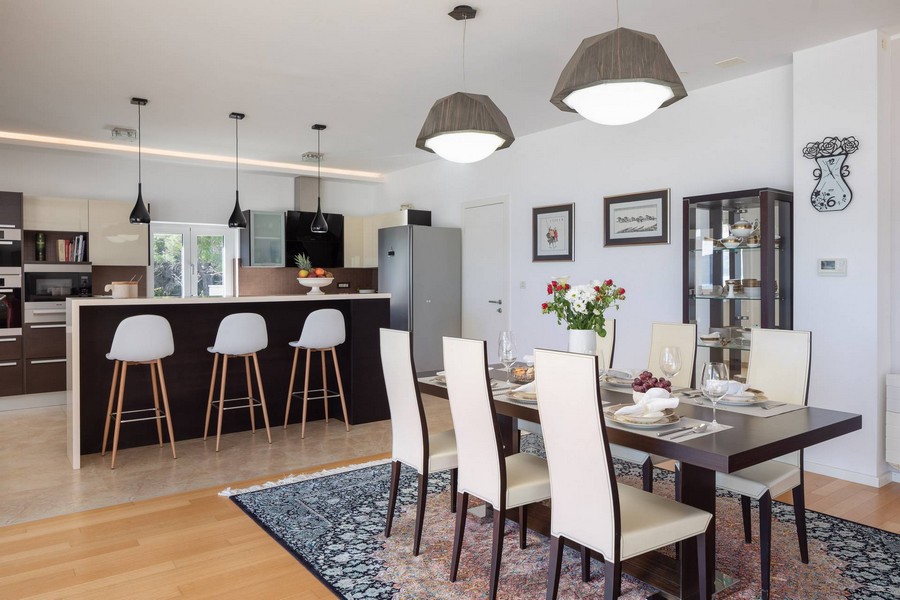Coin repas avec chaises blanches devant la cuisine ouverte avec comptoir