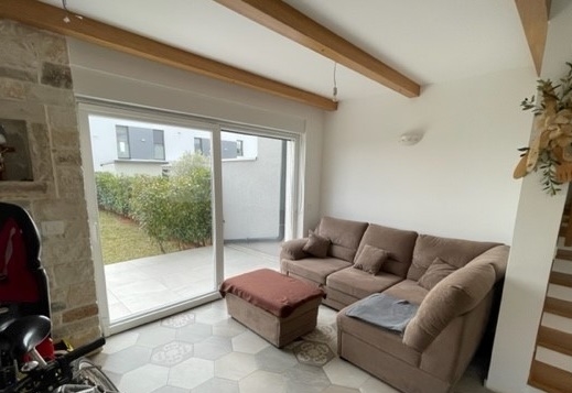 Séjour avec canapé beige et mur en pierre naturelle près de la fenêtre