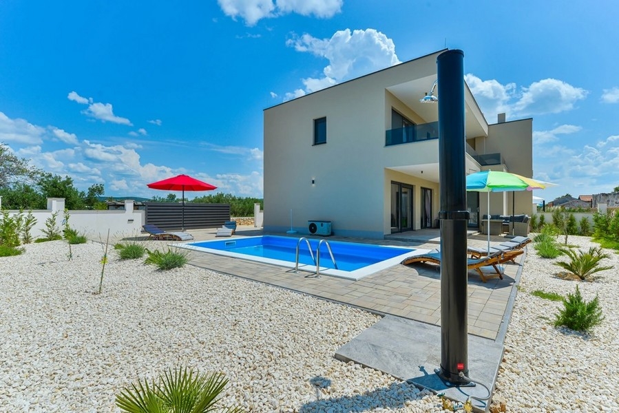 Villa avec piscine et parasols dans un jardin de gravier