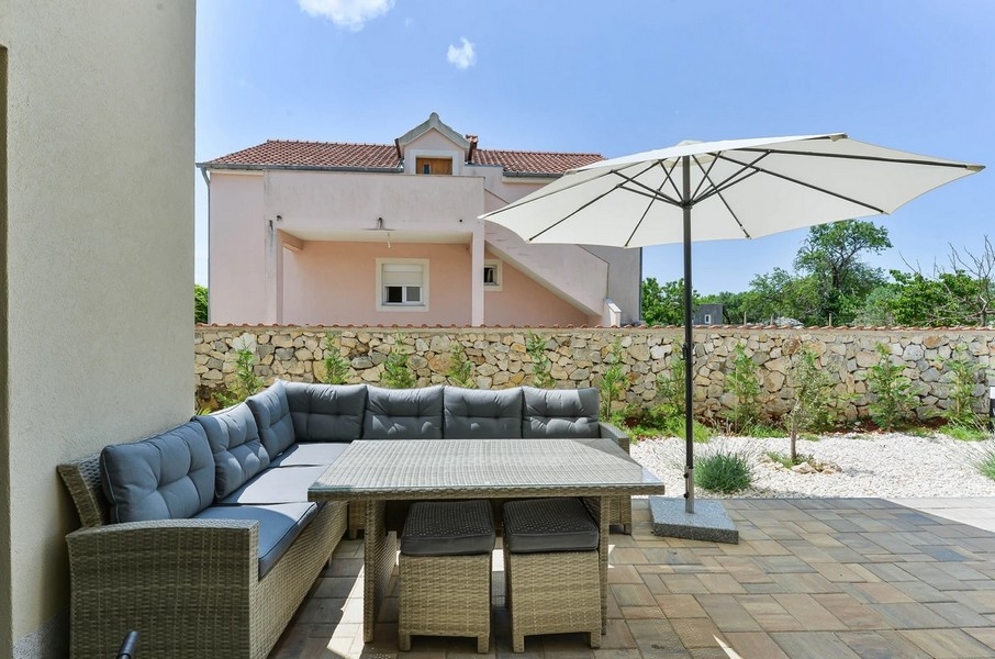 Lounge avec table à manger et parasol devant le mur en pierre naturelle
