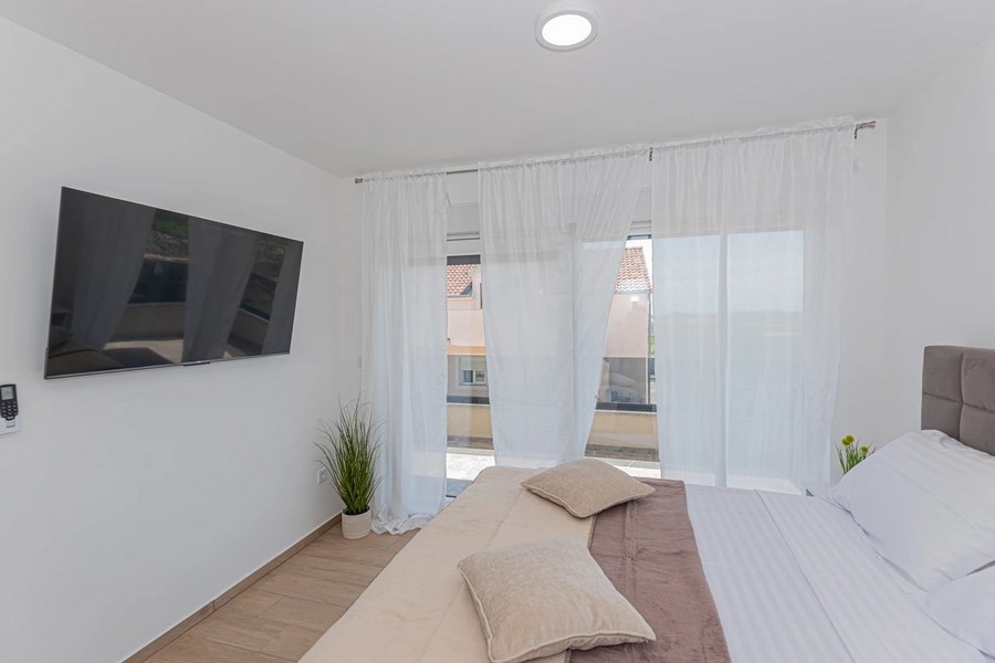 Chambre avec télévision et rideaux à la porte du balcon