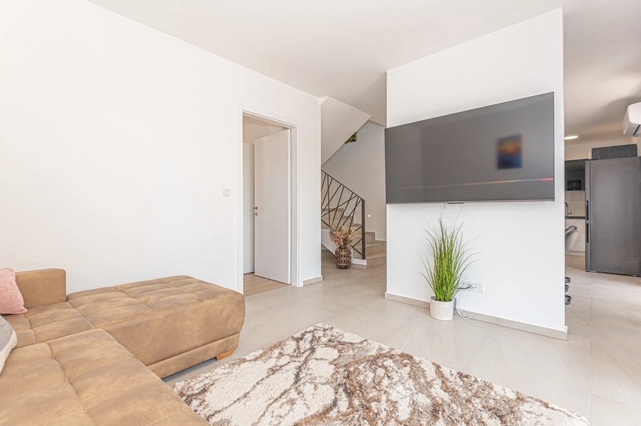 Séjour avec canapé beige et escalier à l'arrière-plan