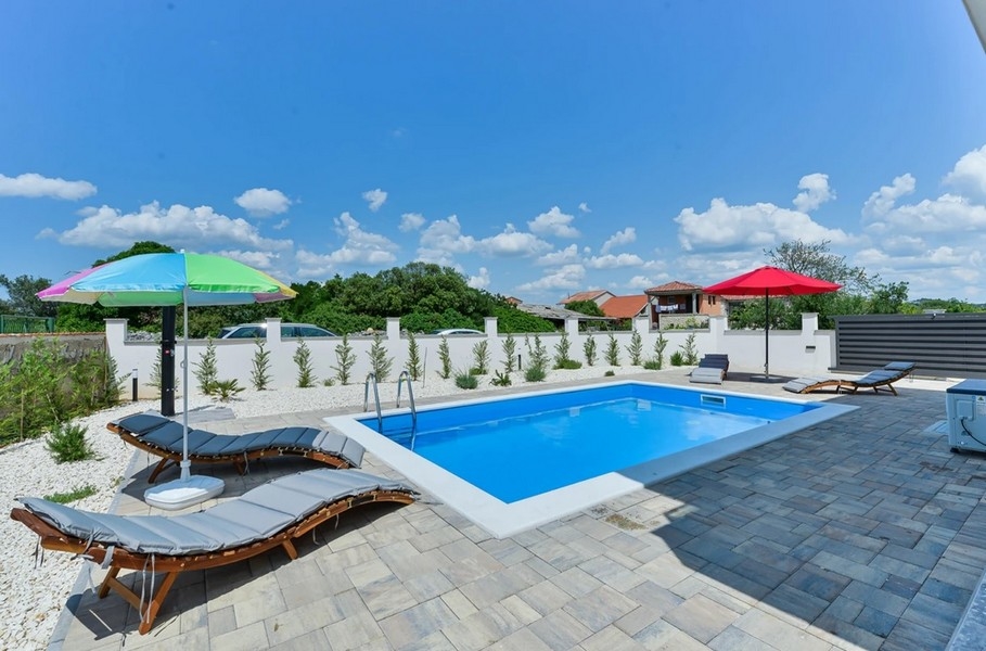 Piscine avec parasols colorés et transats sur le dallage