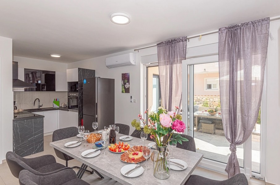 Table dressée devant la cuisine avec porte donnant sur la terrasse
