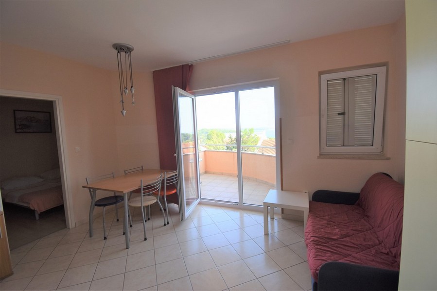 Coin repas et canapé avec vue par la porte ouverte du balcon