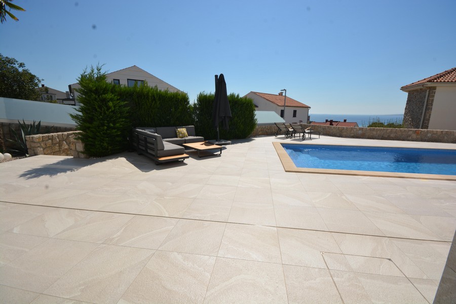 Grande terrasse de la piscine avec lounge et haie en bordure