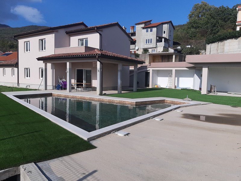 Maison avec terrasse couverte et longue piscine dans le jardin