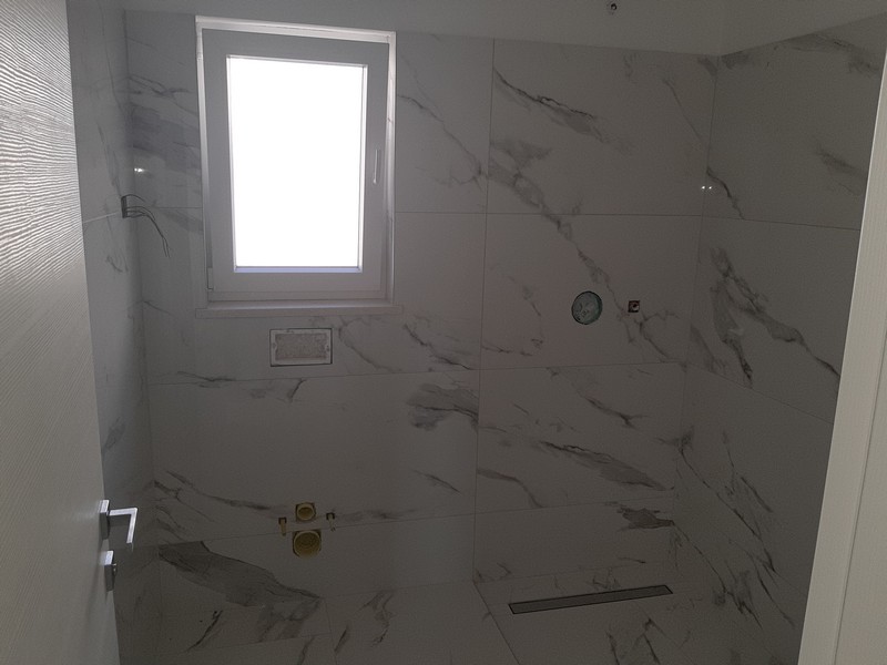 Salle de bains avec carrelage effet marbre et fenêtre