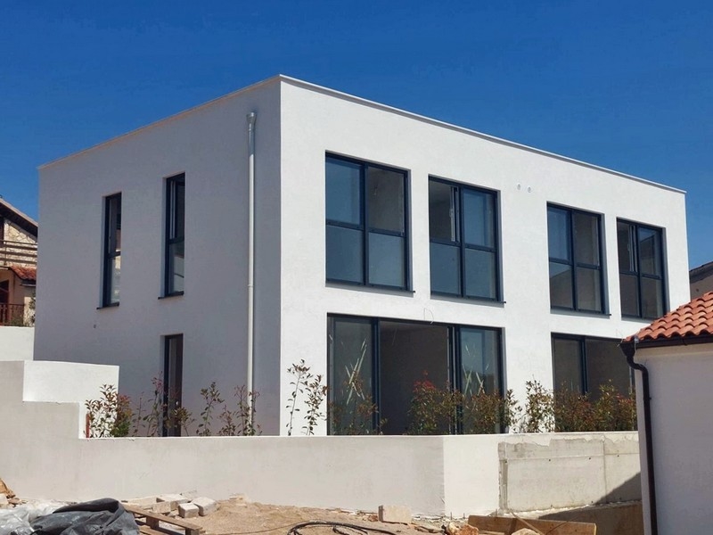 Immeuble neuf blanc avec fenêtres foncées derrière le mur