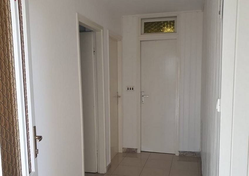 Couloir avec portes blanches et imposte au-dessus de la porte de l'appartement