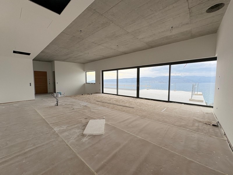 Séjour en gros œuvre avec béton apparent et façade vitrée donnant sur la mer