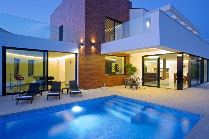 Villa à façade en bois et piscine éclairée au crépuscule